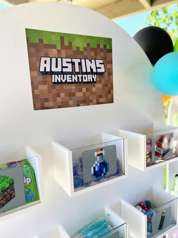 A real goodie wall display with white shelves, Minecraft-themed 'Austin's Inventory' signage and pixel-art treat boxes